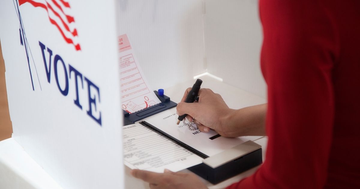 The above stock photo shows a person voting in a polling place.
