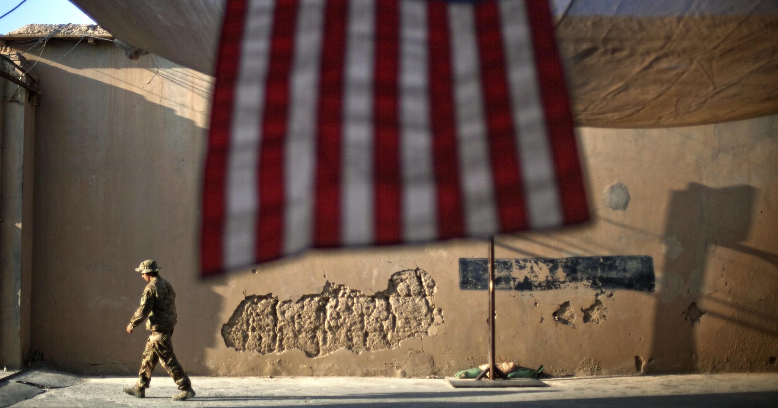 A U.S. Army soldier walks past an American flag at Forward Operating Base Bostick in Kunar province, Afghanistan, on Sept. 11, 2011.