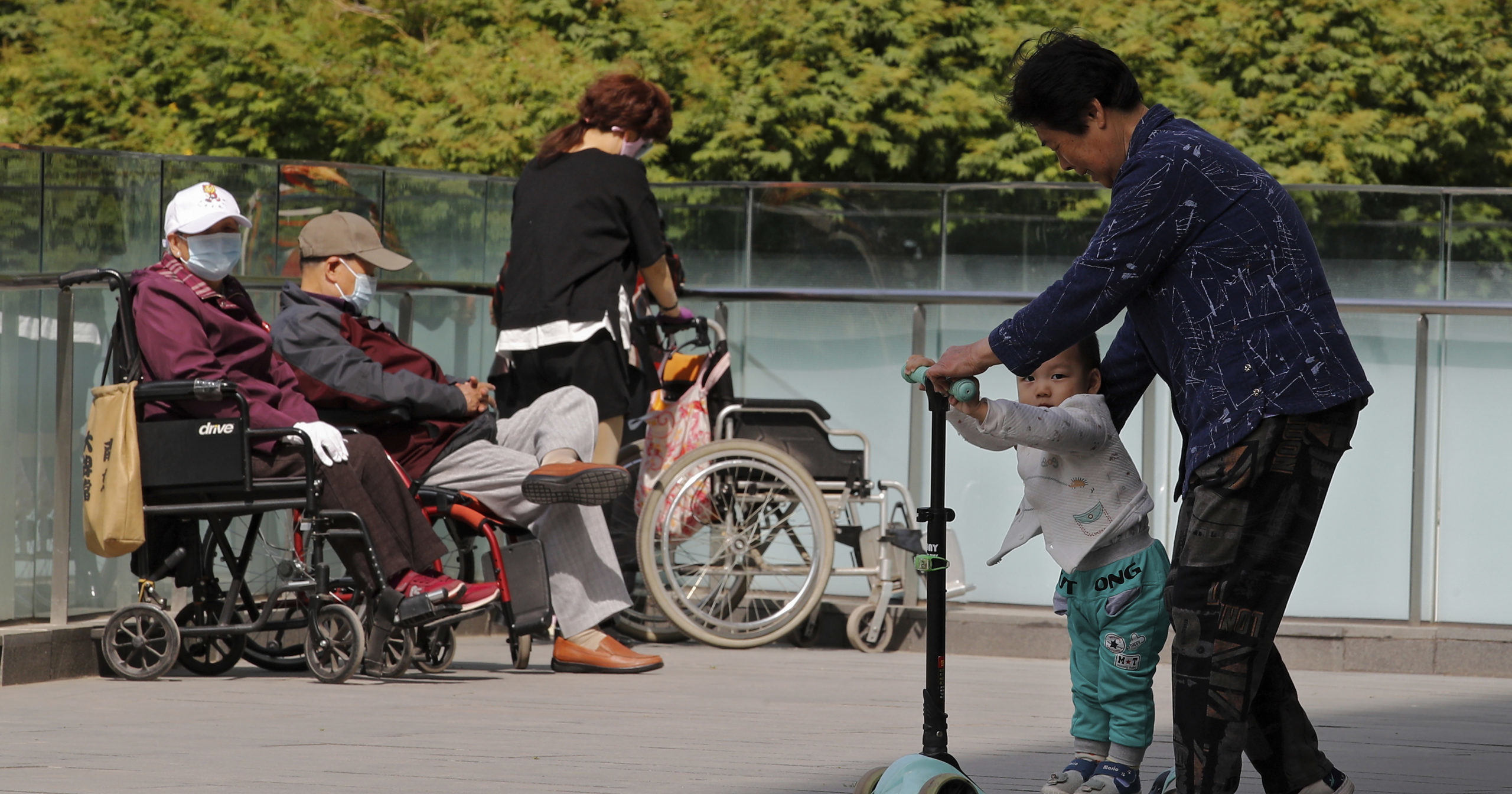A woman plays with a child near elderly people in wheelchairs in Beijing on Monday.