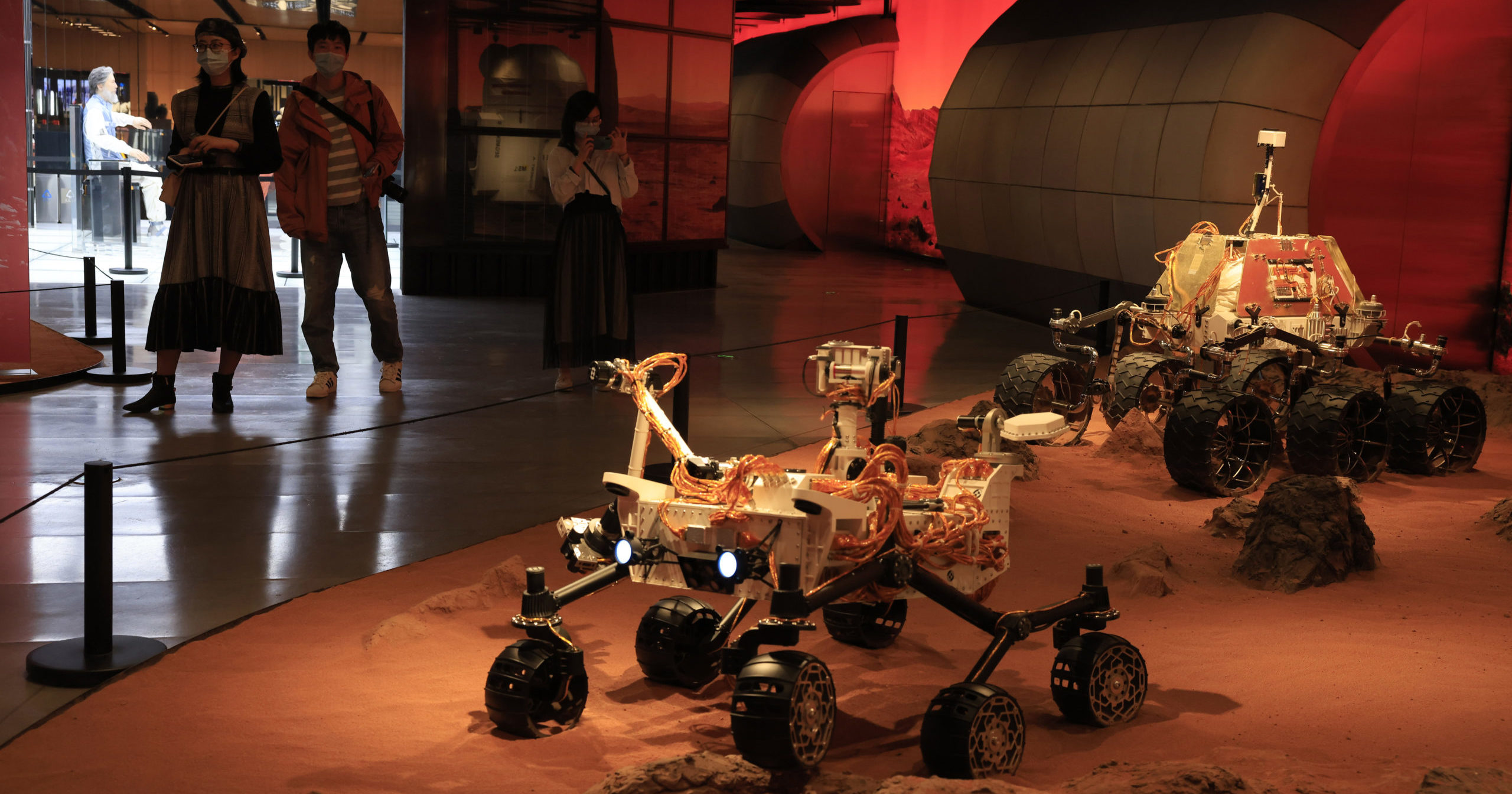 Visitors pass by an exhibition depicting rovers on Mars in Beijing on Friday