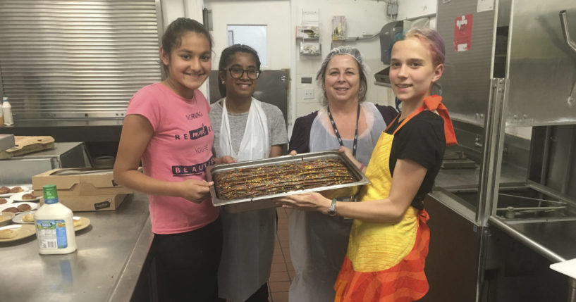 From left, Vedika Jawa, Anika Garikipati, Monica Quintana and Caitlin Starmer pose with freshly baked desserts inside the Abode Services homeless shelter in Fremont, California, on April 13, 2018.
