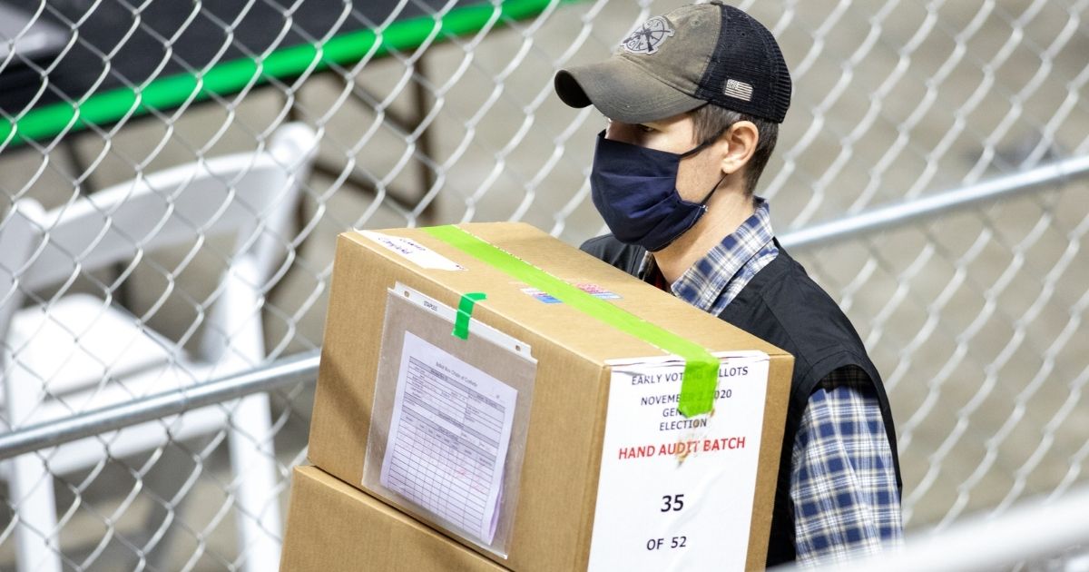 A contractor working for Cyber Ninjas, who was hired by the Arizona State Senate, transports ballots from the 2020 general election at Veterans Memorial Coliseum on May 1, 2021, in Phoenix.