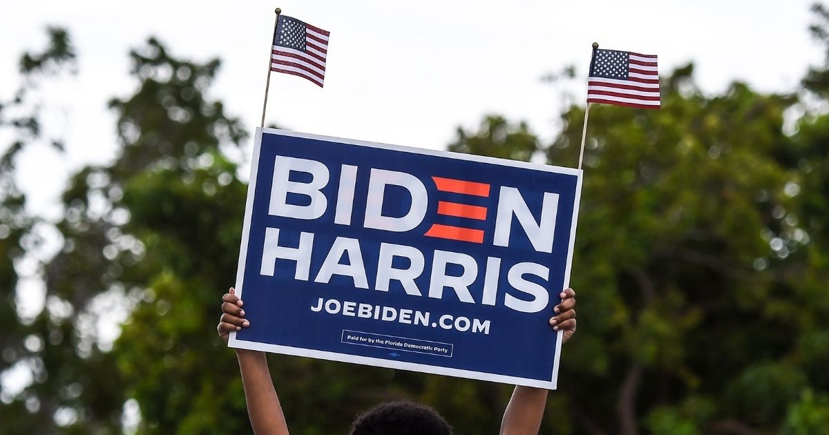 A supporter of Joe Biden holds a sign as they wait for former President Barack Obama to speak at a Biden-Harris drive-in rally in Miami on Oct. 24, 2020.