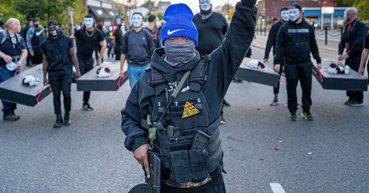 A member of the Minnesota Freedom Fighters wears a bulletproof vest and holds up his fist as he marches during a demonstration in Saint Paul, Minnesota, on Oct. 8, 2020.