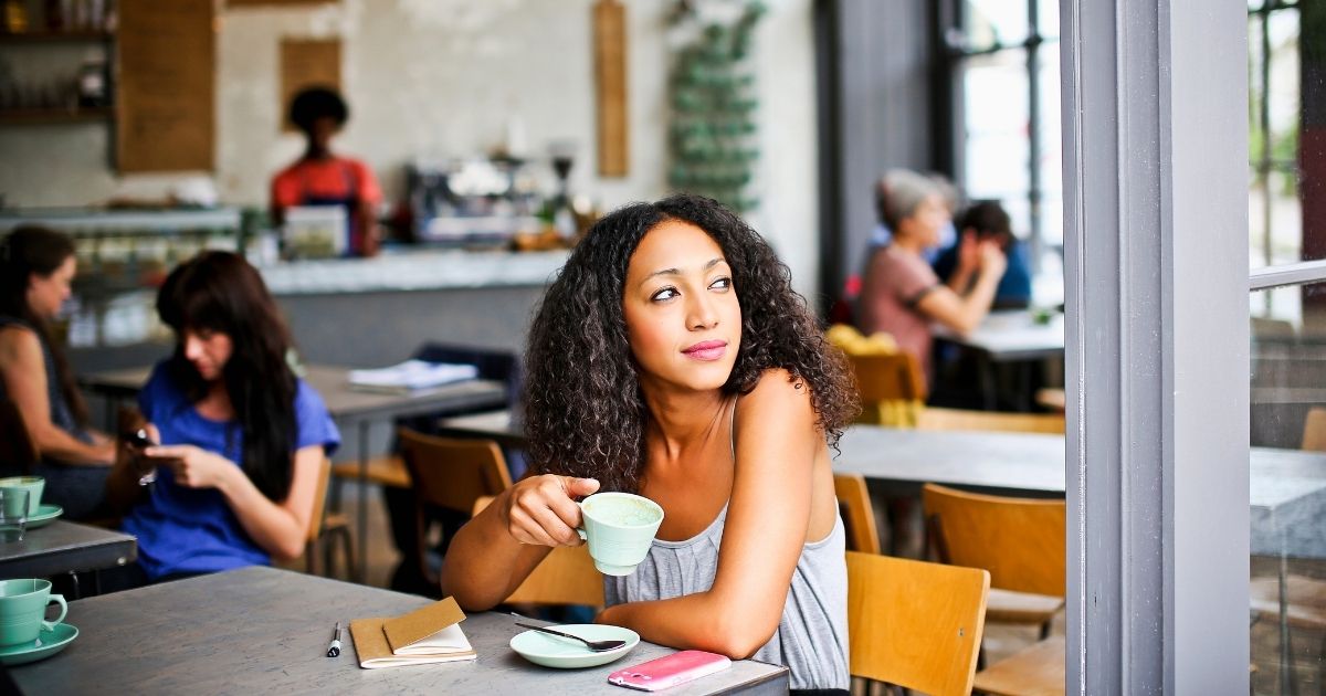 A California cafe is making waves with their take on customers who wear masks and talk about their vaccines. The above stock photo shows a woman in a cafe.