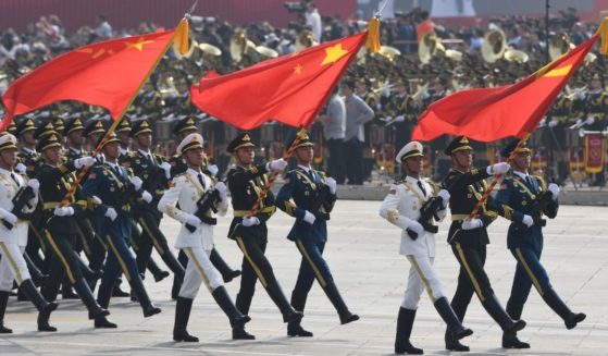 Chinese soldiers march with the national flag, flanked by the flags of the Communist Party of China and the People's Liberation Army during a military parade at Tiananmen Square in Beijing on Oct. 1, 2019.