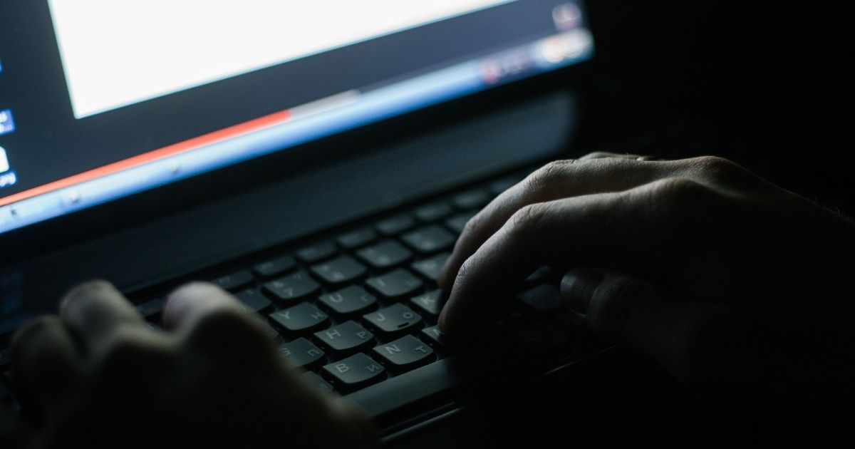 A person uses a keyboard in a dark room.