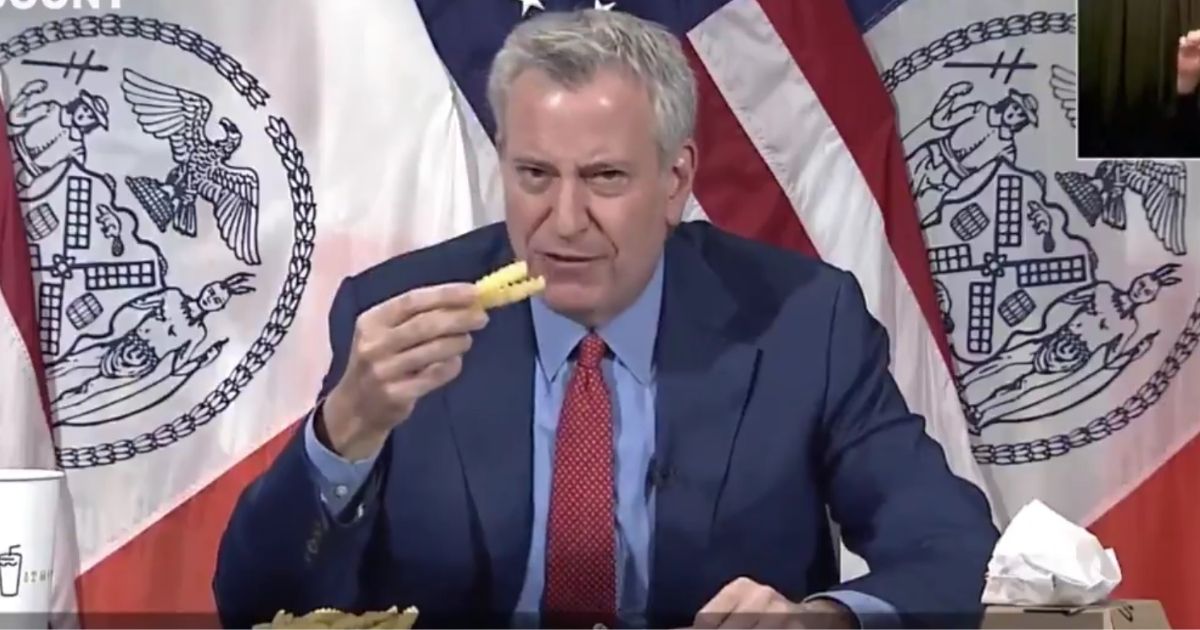Mayor Bill de Blasio eats french fries during a news conference.