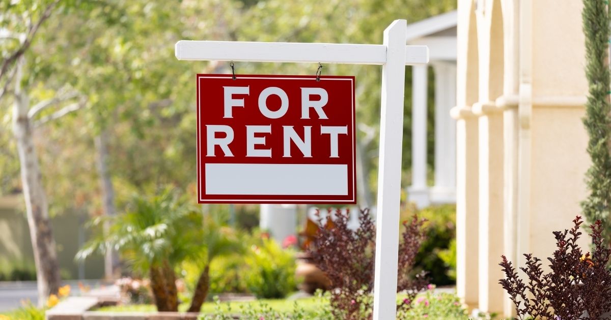 A 'For Rent' sign in a front yard.