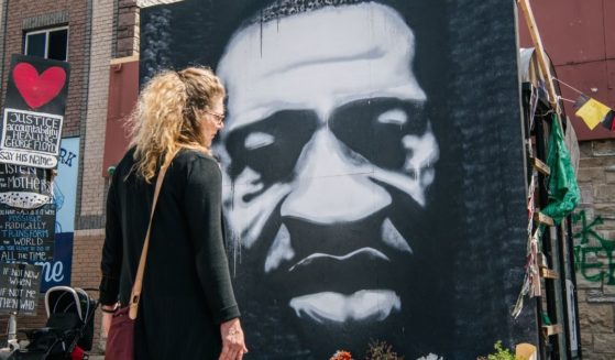 A woman stands in front of a mural of George Floyd on Tuesday in Minneapolis.