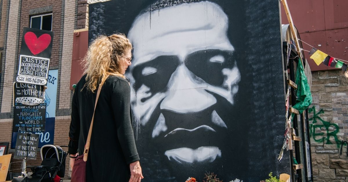 A woman stands in front of a mural of George Floyd on Tuesday in Minneapolis.