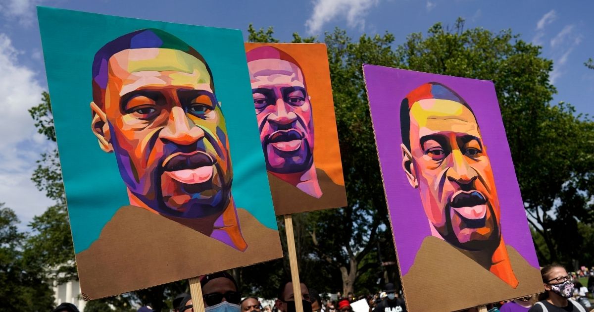 In this Aug. 28, 2020, file photo, people carry posters with George Floyd on them as they march from the Lincoln Memorial to the Martin Luther King Jr. Memorial in Washington D.C.