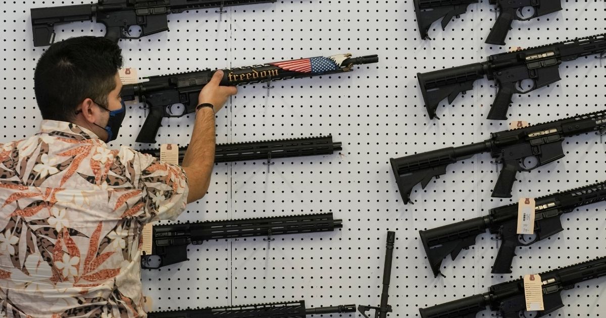A worker hangs a custom made AR-15 style rifle on a wall at Davidson Defense in Orem, Utah, on Feb. 4.