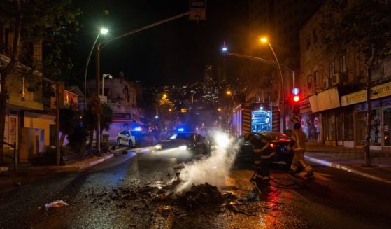 Firefighters put out a fire that was lit by rioters in the Hadar neighborhood of Haifa, Israel, on Thursday.