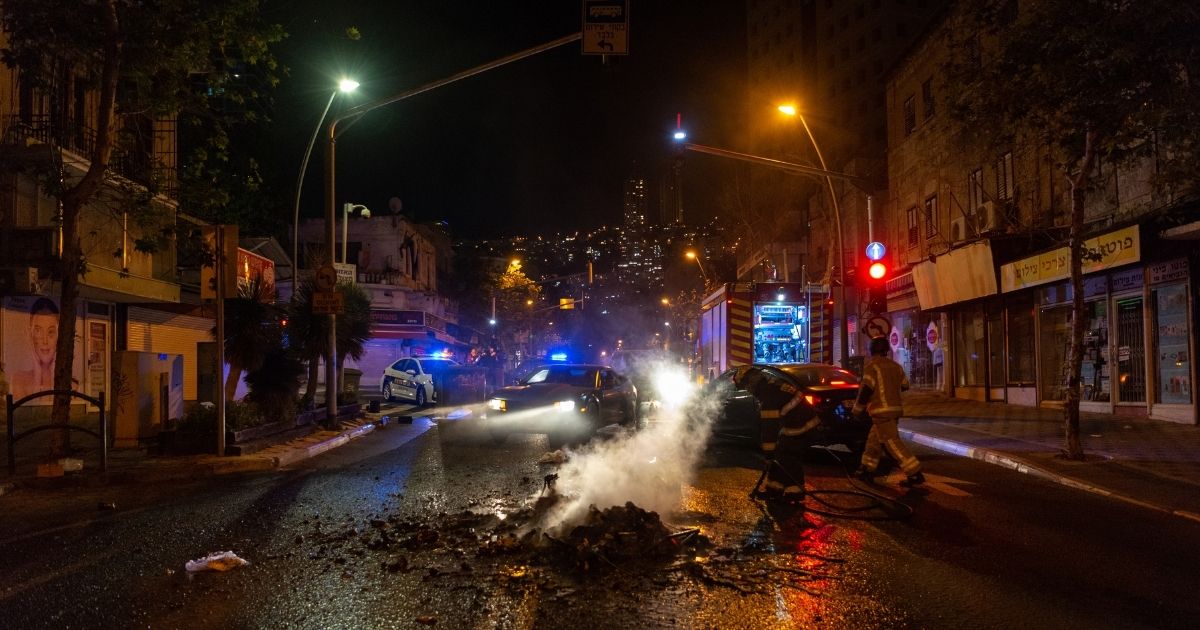 Firefighters put out a fire that was lit by rioters in the Hadar neighborhood of Haifa, Israel, on Thursday.