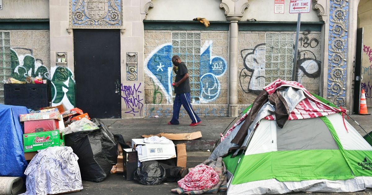 A man walks past tents housing the homeless on the streets in the Skid Row community of Los Angeles on April 26.