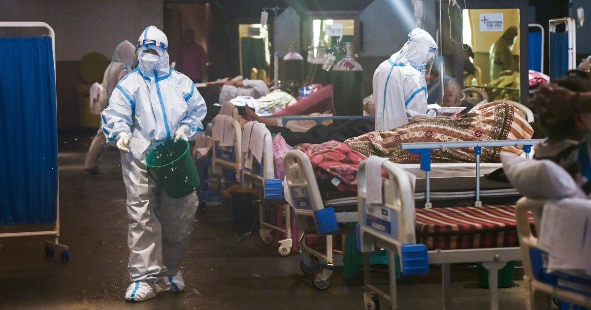 Health workers wearing a personal protective equipment suits attend to patients inside a banquet hall temporarily converted into a COVID-19 ward in New Delhi on May 1.