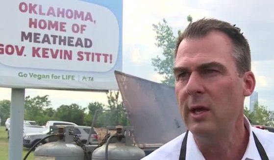 Oklahoma Gov. Kevin Stitt grills meat underneath a PETA sign in Oklahoma City.