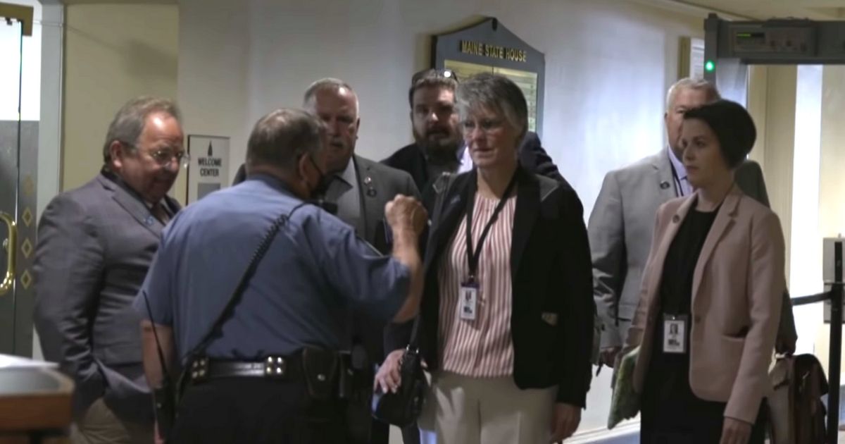 Several Maine state House representatives enter the state Capitol building wearing no masks.