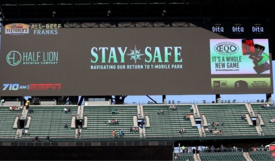 COVID-19 messages are shown on a screen behind socially distanced fans before a game between the Seattle Mariners and Houston Astros at T-Mobile Park on April 17.