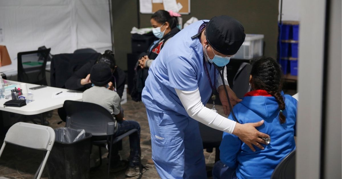 A migrant child gets a medical check-up before entering the intake area in the Department of Homeland Security holding facility on March 30, 2021, in Donna, Texas.