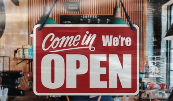 A business sign that says 'Come in, we're open' is seen on a restaurant window.