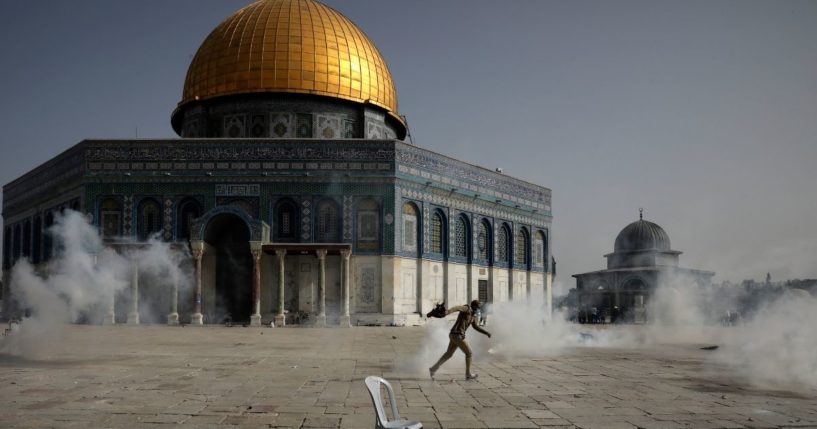 A Palestinian man runs away from tear gas during clashes with Israeli security forces in front of the Dome of the Rock Mosque at the Al Aqsa Mosque compound in Jerusalem's Old City on Monday.