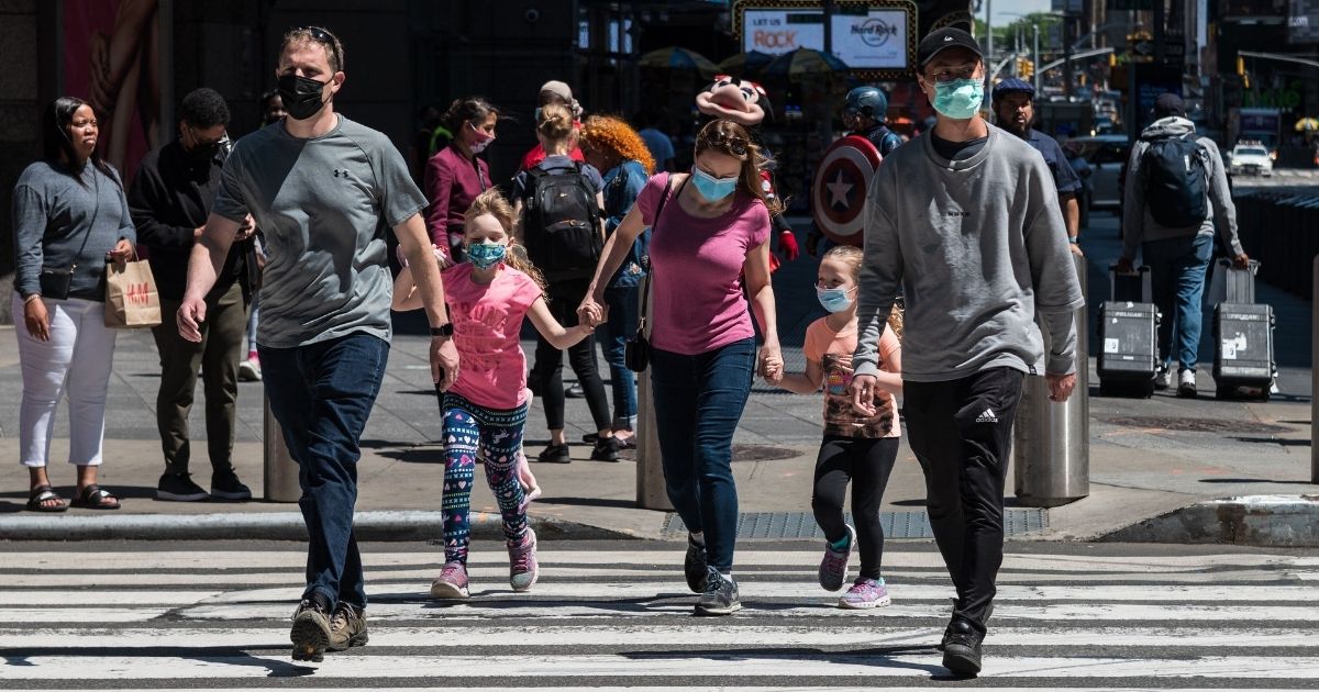 People wearing masks walk through Times Square on Monday in New York City.