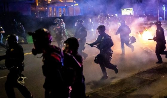 Portland police officers chase demonstrators after a riot was declared during a protest on April 12, 2021, in Portland, Oregon.