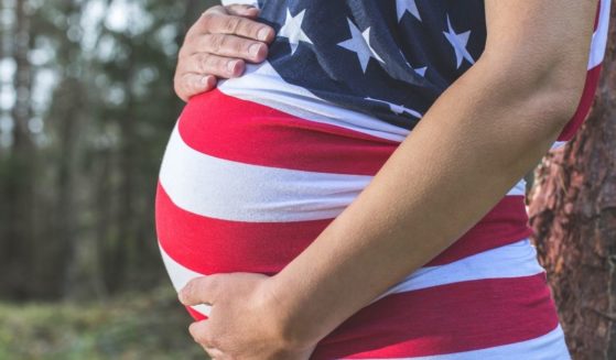 A pregnant woman wears an American flag shirt.