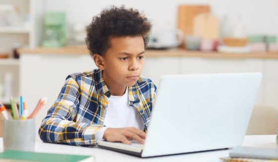 A student is pictured attending class remotely in the stock image above.