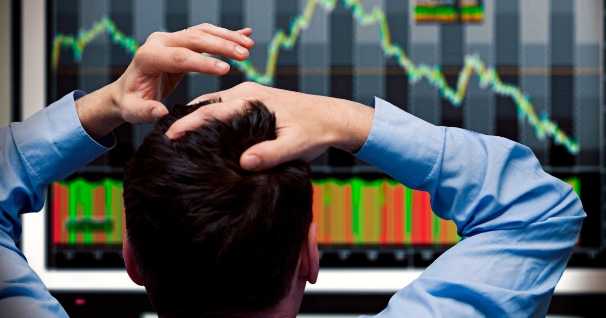 In this stock photo, an investor looks at stock prices dropping on a screen.