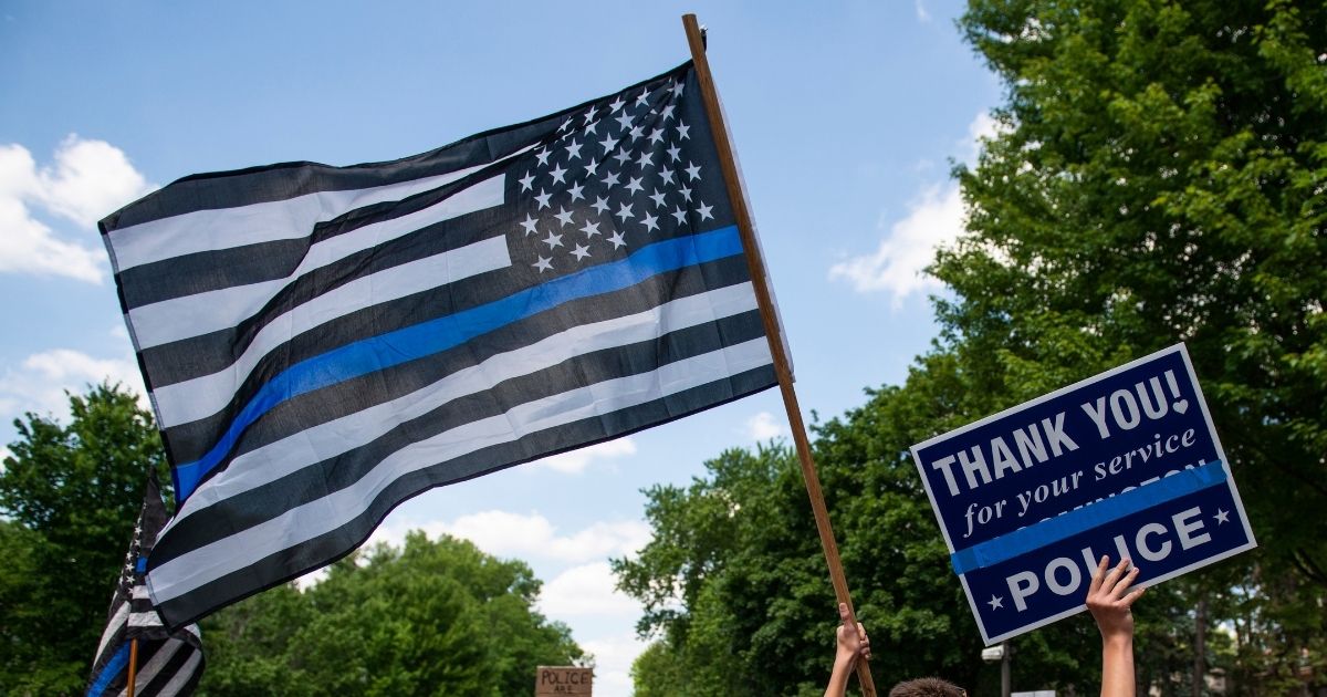 A demonstrator holds a "Thin Blue Line" flag and a sign in support of police during a protest outside the Governors Mansion on June 27, 2020, in St Paul, Minnesota.