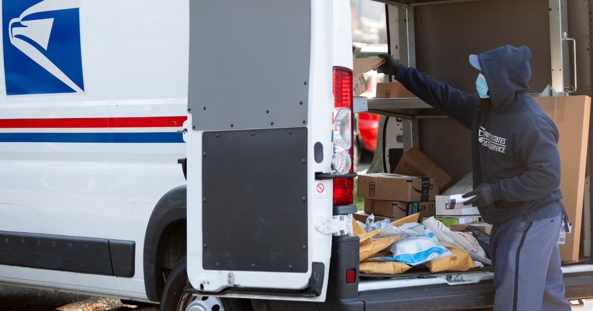 A mailman loads a postal truck with packages at a United States Postal Service post office location in Washington, D.C., on April 16, 2020.