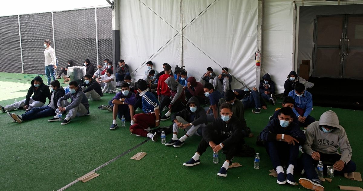 Young minors sit on the ground of a holding facility in Donna, Texas, on March 30.
