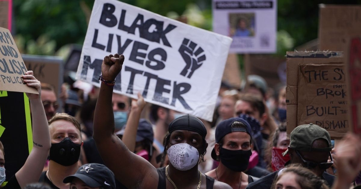 Protesters hold a "Black Lives Matter" sign and raise their fists as they march through Greenwich Village in a demonstration over the death of George Floyd on June 19, 2020, in New York.