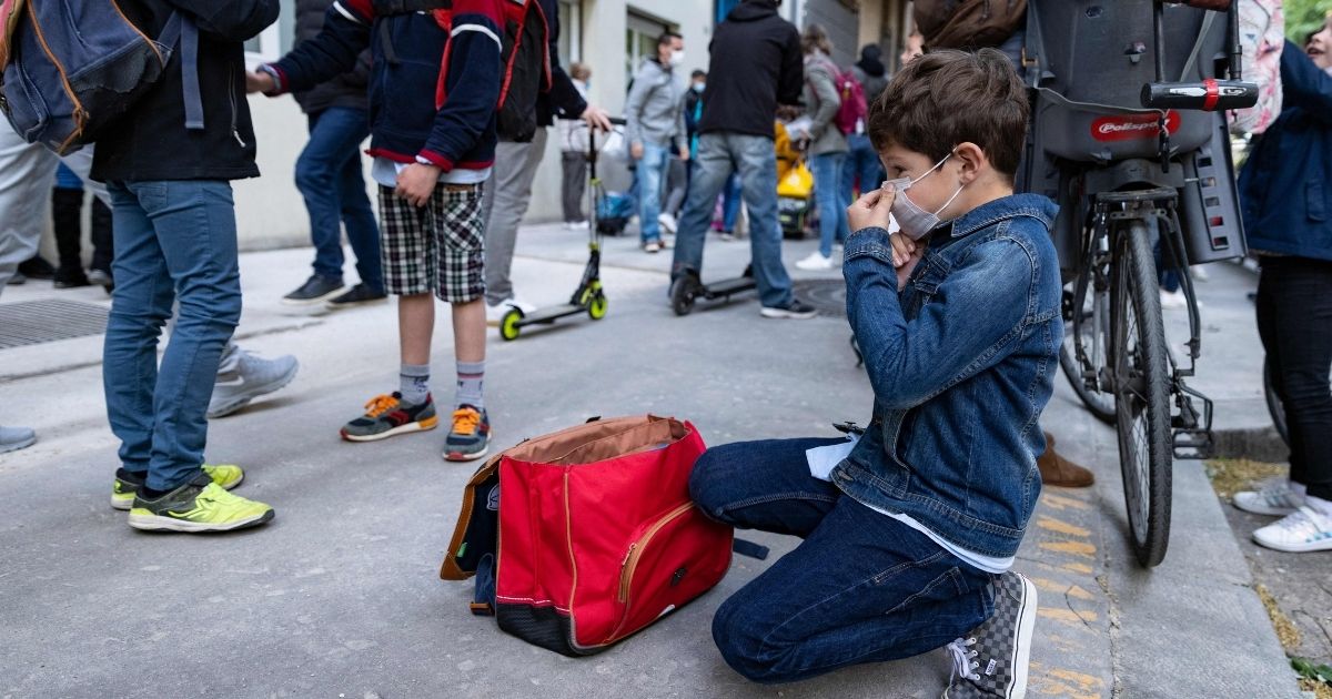 A boy adjusts his face mask before entering primary school in Paris April 26.
