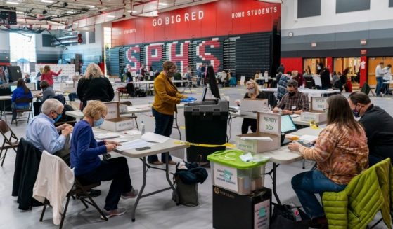 Poll workers feeds a voting tabulation machine with absentee ballots in the gym at Sun Prairie High School on Nov. 3, 2020, in Sun Prairie, Wisconsin.