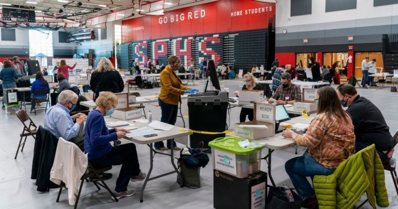 Poll workers feeds a voting tabulation machine with absentee ballots in the gym at Sun Prairie High School on Nov. 3, 2020, in Sun Prairie, Wisconsin.