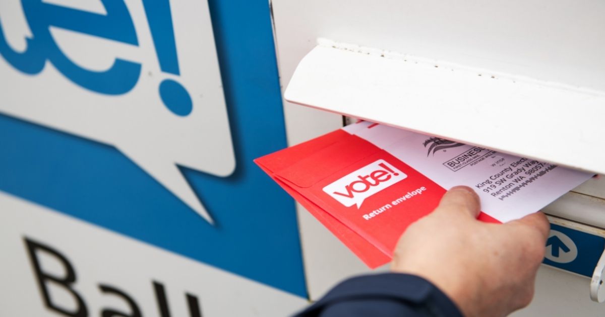 A man places a mail-in ballot in a drop box in the above stock image.