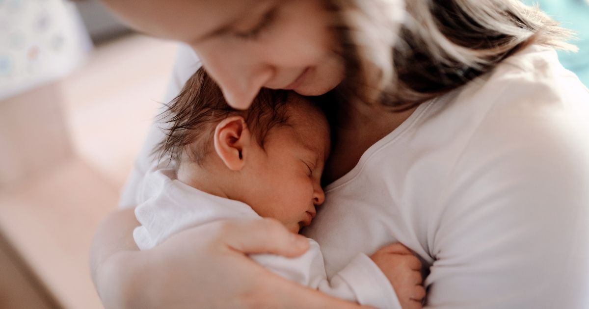 A woman holds a baby in this stock image.