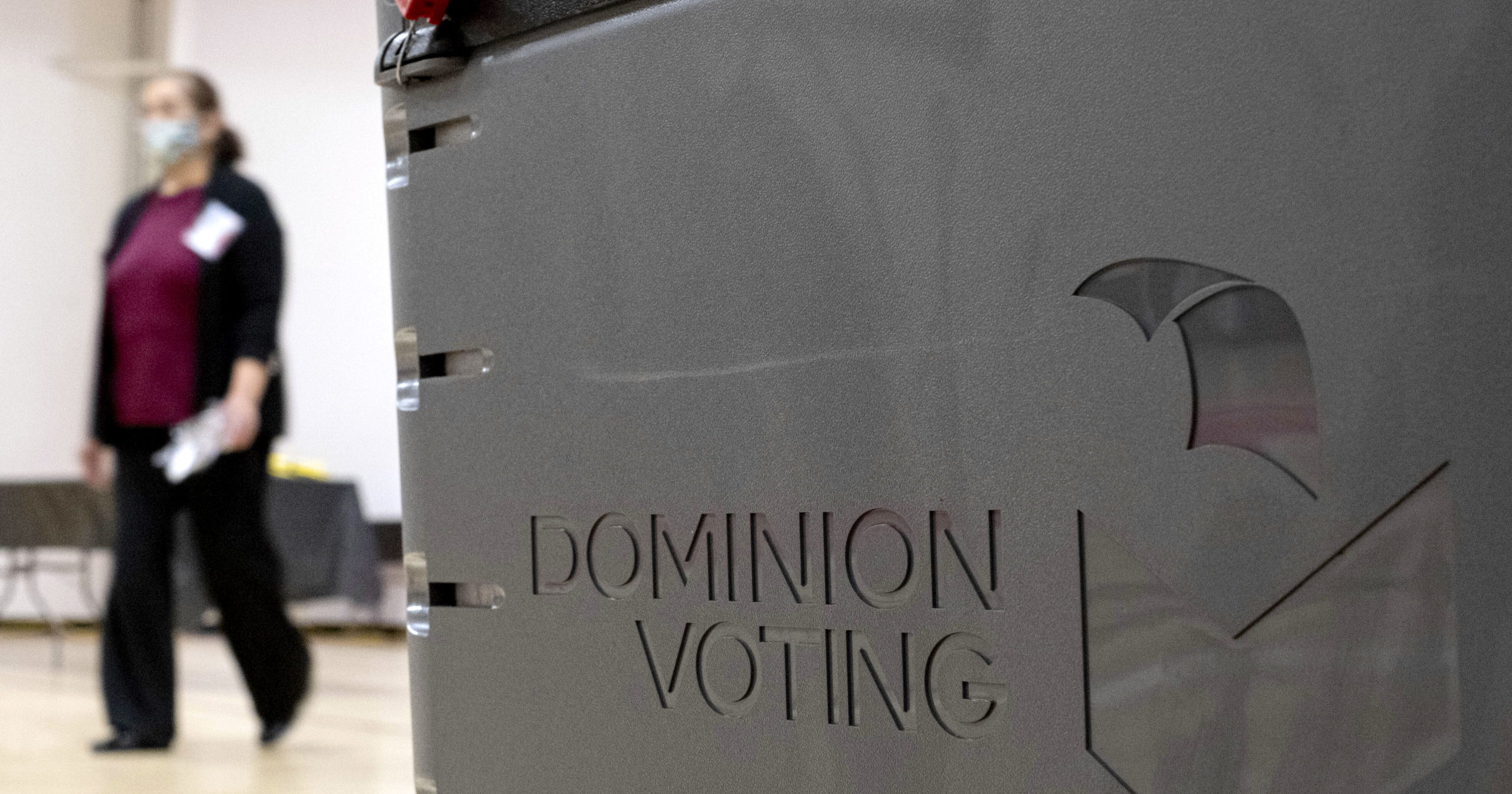 A worker passes a Dominion Voting ballot scanner while setting up a polling location at an elementary school in Gwinnett County, Georgia, on Jan. 4, 2021.