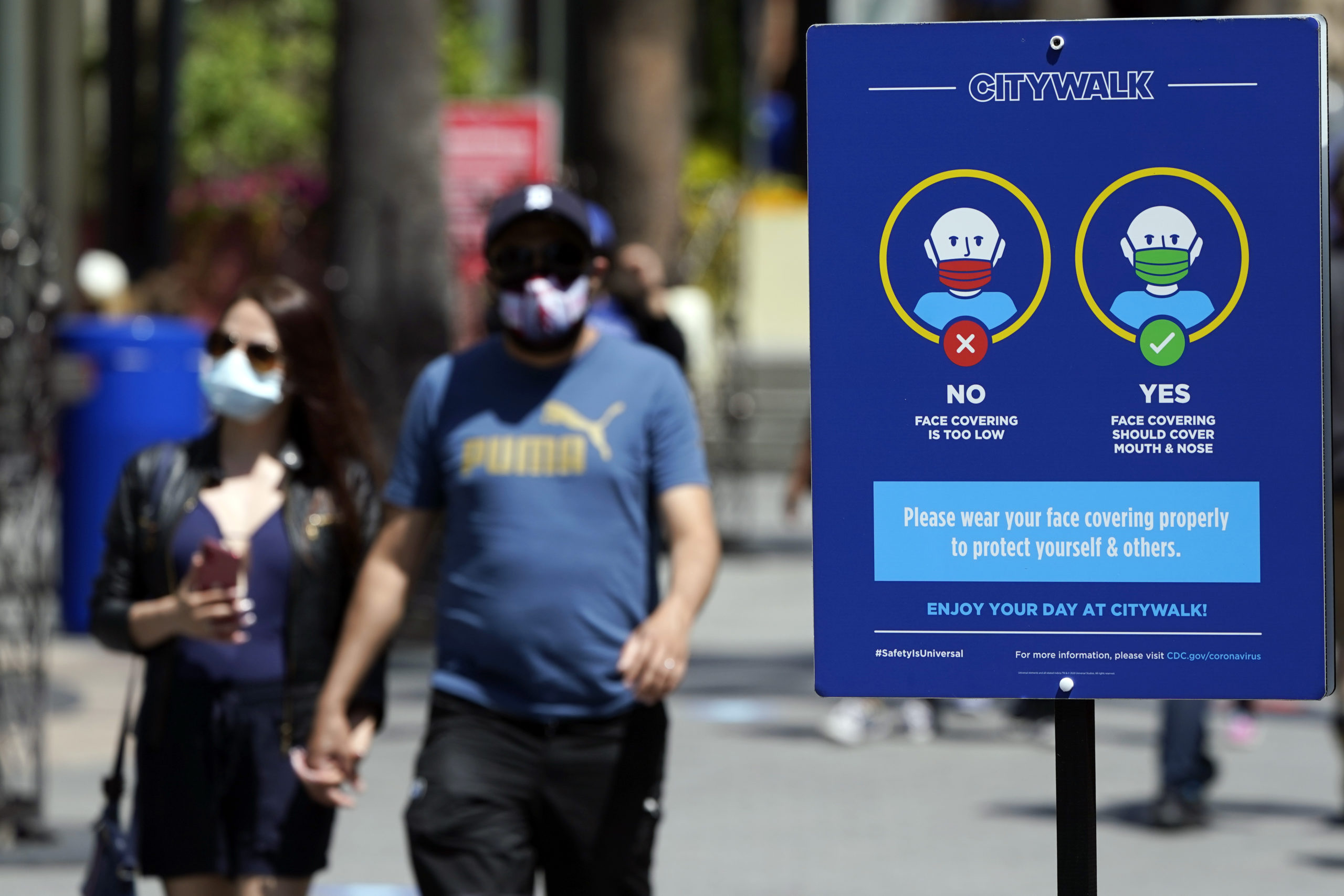 In this Friday photo, signs instruct visitors on the proper way to wear masks at the Universal City Walk in Universal City, California.