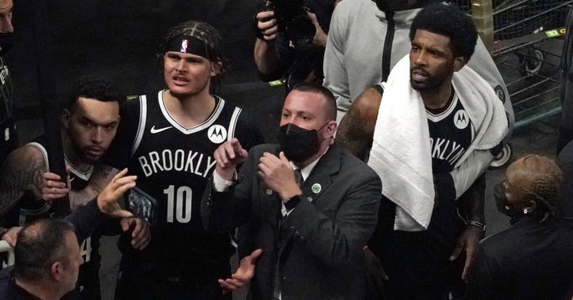 A security guard points as Brooklyn Nets' Kyrie Irving, right with towel, and teammates look up at a fan who reportedly threw a water bottle at him as he left the court after Game 4 during an NBA basketball first-round playoff series on Sunday in Boston.