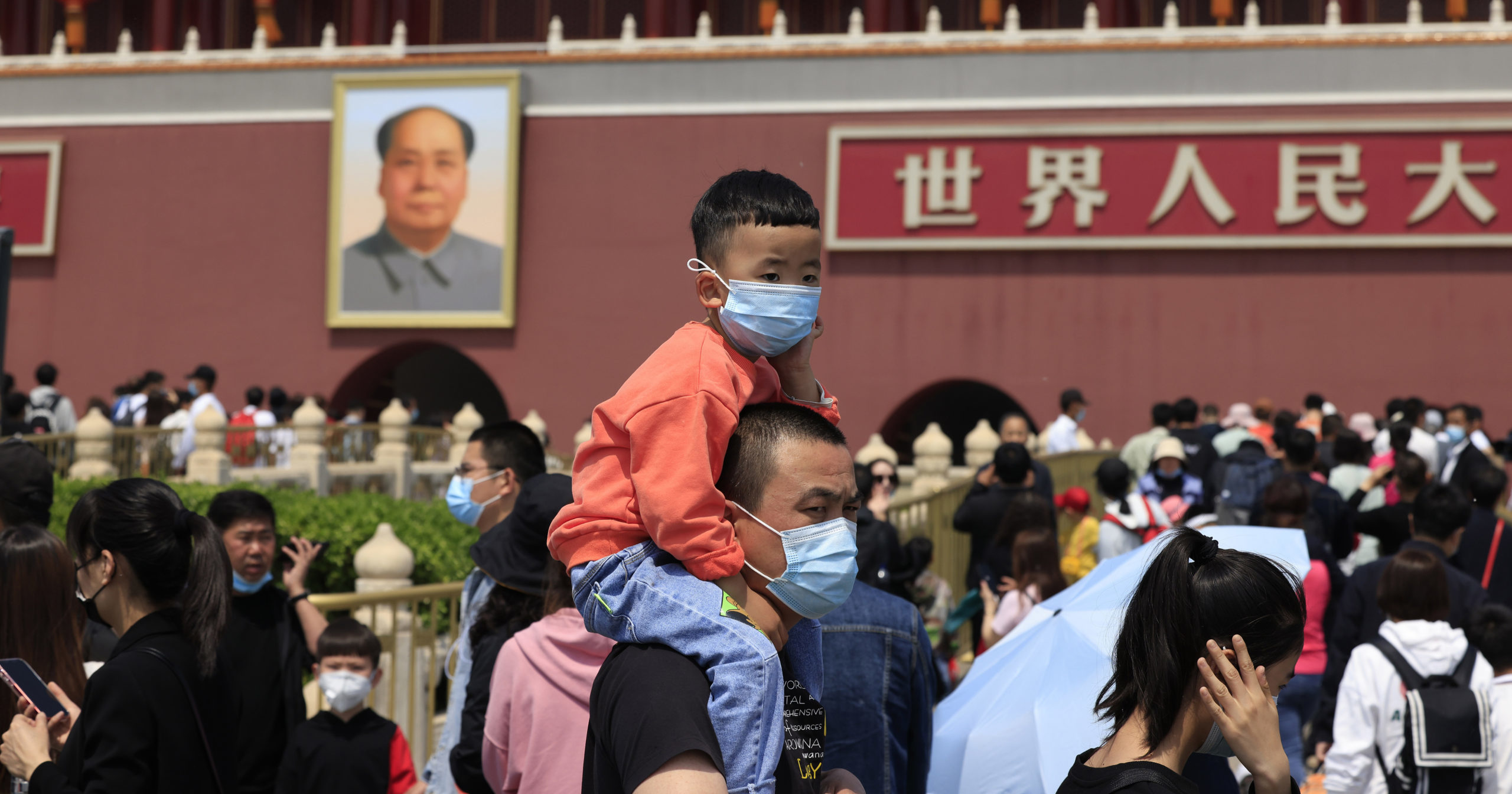 In this May 3, 2021, file photo, a man and child wearing masks visit Tiananmen Gate near the portrait of Mao Zedong in Beijing.