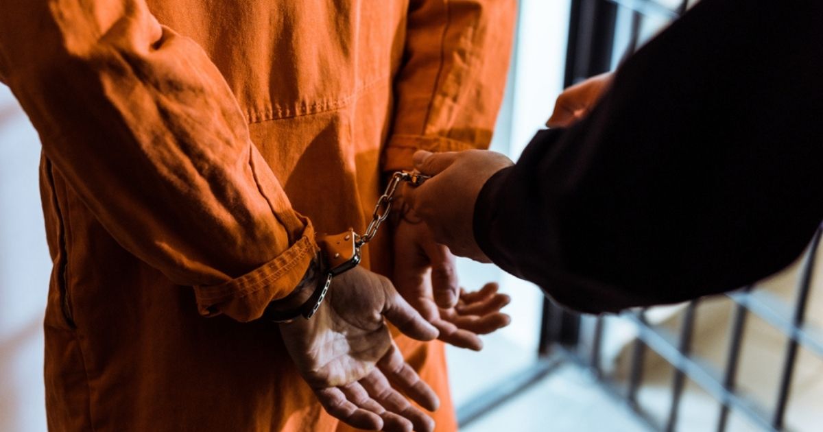 A police officer handcuffs a prisoner in the above stock image.