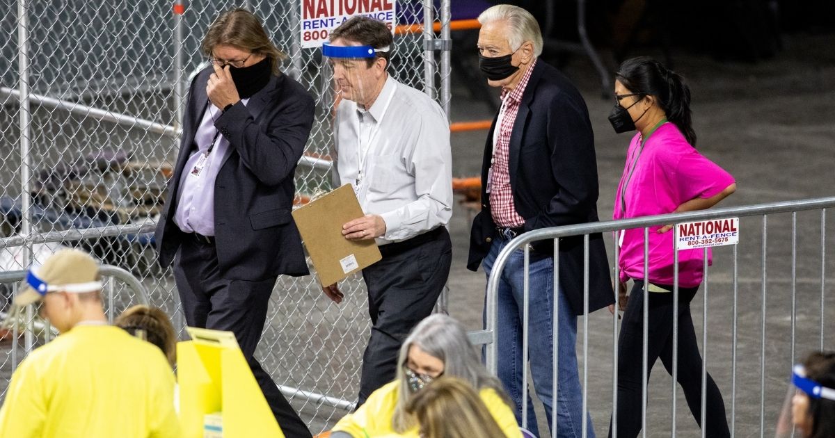 Former Secretary of State Ken Bennett (second from left) works to move ballots from the 2020 general election at Veterans Memorial Coliseum on May 1, 2021, in Phoenix.