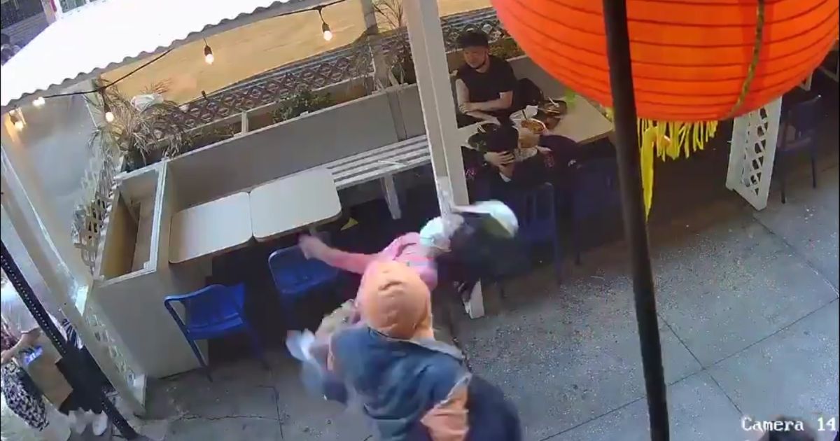 An Asian woman is punched in the face as she walks by a restaurant in Chinatown in New York City on Monday.