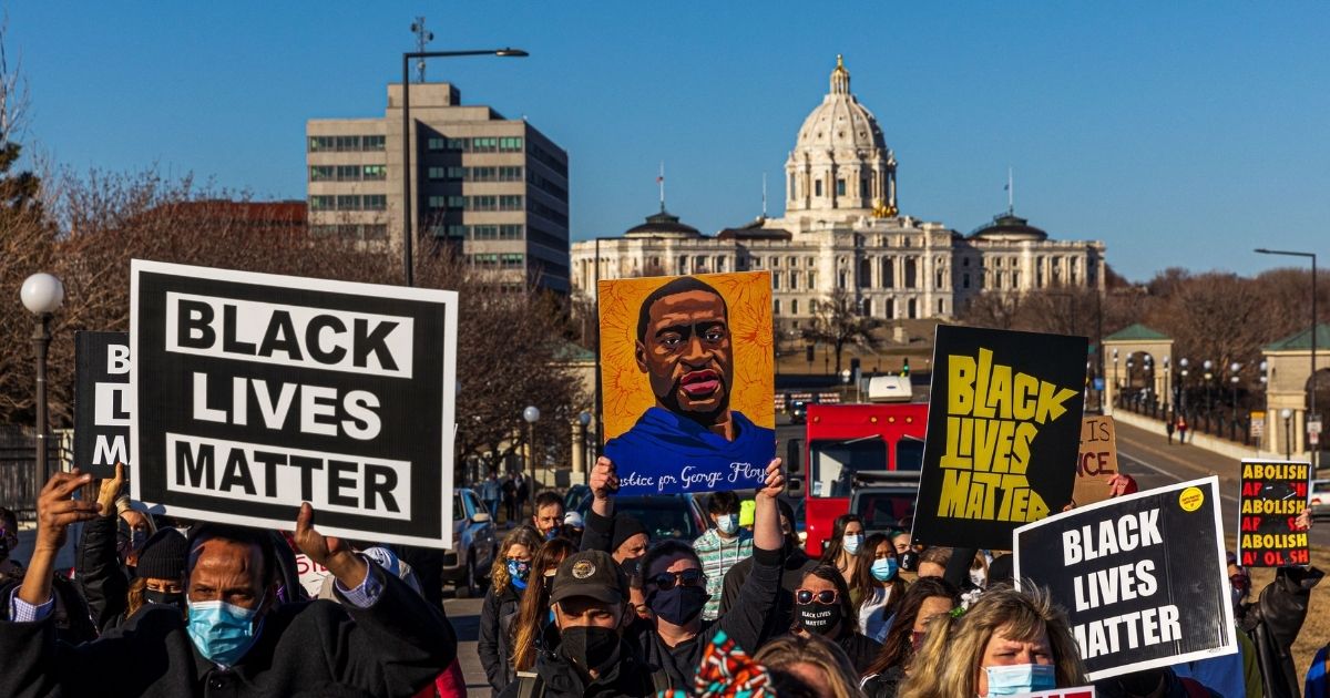 Protesters hold signs during the "Justice for George Floyd" march at the Minnesota State Capitol on March 19, 2021, in Saint Paul, Minnesota.