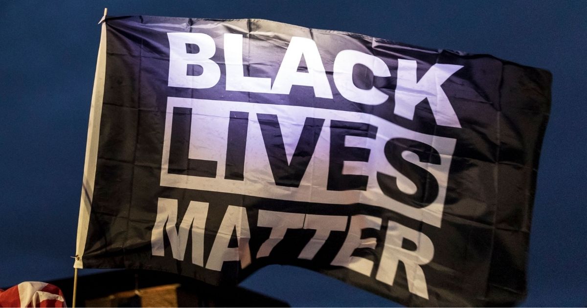 Demonstrators fly a Black Lives Matter flag outside the Brooklyn Center police station in Brooklyn Center, Minnesota on April 14, 2021.